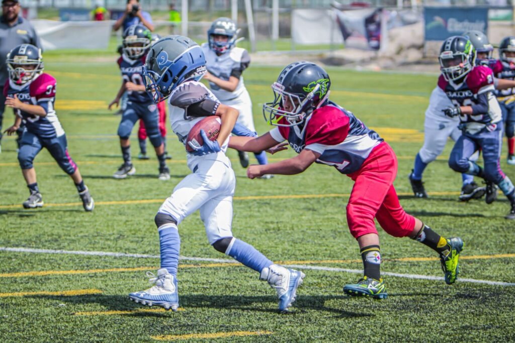 Exciting youth football game featuring young players in protective gear on a sunny day.
